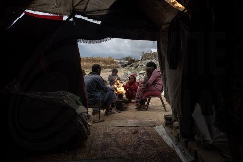 epa12594415 A displaced Palestinian family light a fire for warmth outside their shelter in the city of Khan Younis, in the southern Gaza Strip, 15 December, 2025.  According to the UN around 90 percent of the population or 1.9 million people in Gaza have been displaced since the start of the conflict.  EPA/HAITHAM IMAD