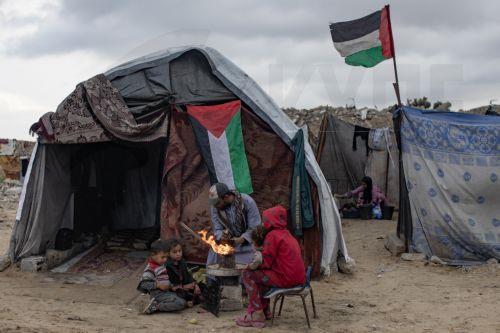 epa12594417 A displaced Palestinian family light a fire for warmth outside their shelter in the city of Khan Younis, in the southern Gaza Strip, 15 December, 2025.  According to the UN around 90 percent of the population or 1.9 million people in Gaza have been displaced since the start of the conflict.  EPA/HAITHAM IMAD