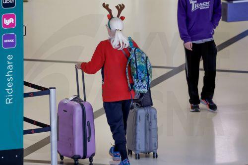 epa12609412 An air passenger wearing antlers collects her luggage while transiting through Hartsfield-Jackson Atlanta International Airport during the busy Christmas holiday travel season in Atlanta, Georgia, USA, 22 December 2025. Weather could cause delays for both air travelers and drivers.  EPA/ERIK S. LESSER