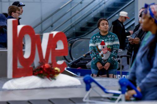 epa12609417 An air passenger wearing a holiday sweater waits for her luggage while transiting through Hartsfield-Jackson Atlanta International Airport during the busy Christmas holiday travel season in Atlanta, Georgia, USA, 22 December 2025. Weather could cause delays for both air travelers and drivers.  EPA/ERIK S. LESSER