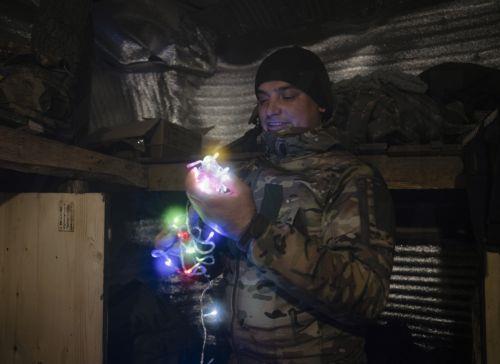 epa12618044 A handout photo made available by the press service of the 93rd 'Kholodnyi Yar' Separate Mechanized Brigade of the Ukrainian Armed Forces shows a serviceman, call sign 'Synok' (Sonny), from the brigade preparing a New Year garland at an undisclosed location near the frontline city of Kostyantynivka, Donetsk region, eastern Ukraine, 30 December...