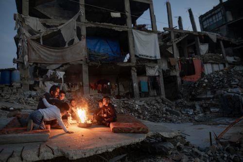 epa12618098 Displaced Palestinians warm themselves near a fire among the ruins of their destroyed home in Khan Yunis, southern Gaza Strip, 30 December 2025, amid a ceasefire between Israel and Hamas.  EPA/HAITHAM IMAD