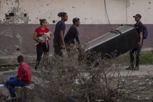 epa12627768 People move a refrigerator in front of a building damaged by an explosive device, in Catia La Mar, Venezuela, 04 January 2026.  EPA/MIGUEL GUTIÉRREZ