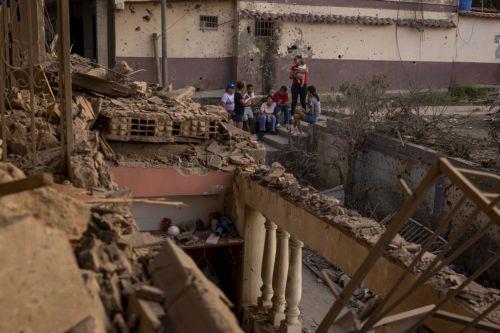 epa12627771 People look at a building damaged by an explosive device, in Catia La Mar, Venezuela, 04 January 2026.  EPA/MIGUEL GUTIÉRREZ