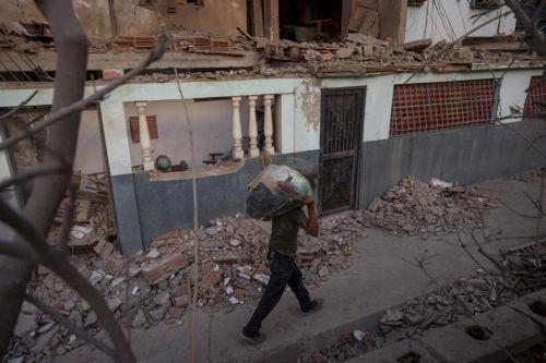 epa12627772 A person walks past a building damaged by an explosive device, in Catia La Mar, Venezuela, 04 January 2026.  EPA/MIGUEL GUTIÉRREZ