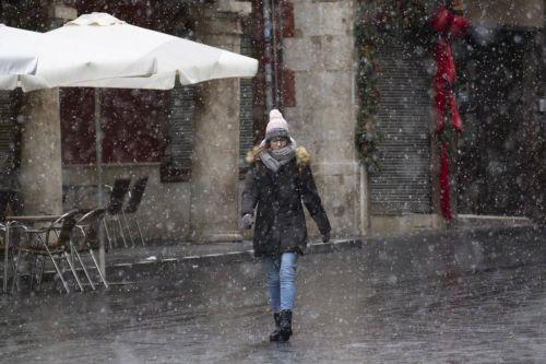 epa12628327 A woman walks on a street amid snow in Teruel, central Spain, 05 January 2026, due to Storm Francis.  EPA/ANTONIO GARCIA
