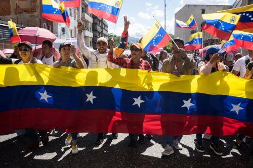 epa12639423 People wave Venezuelan flags and hold a banner during a demonstration in Caracas, Venezuela, 09 January 2026. Supporters of Venezuelan President Nicolas Maduro called for his release after he and his wife, Cilia Flores, were captured by US forces during a military operation on 03 January 2026. Maduro and Flores are being held in the United...