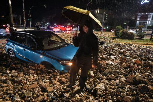 epa12669142 A person walks on a road covered with rocks and mud during a storm in Voula near Athens, Greece, 21 January 2026. A wave of severe weather affecting Greece brings heavy rain, thunderstorms, snowfall and gale-force winds.  EPA/GEORGE VITSARAS