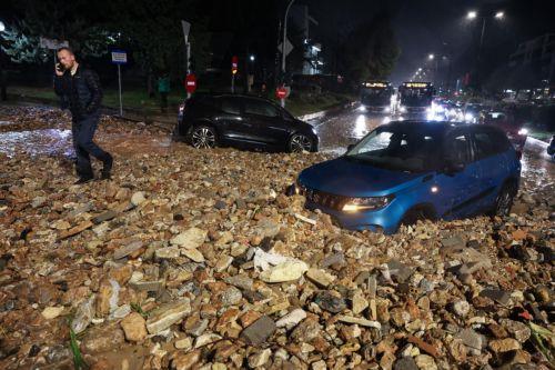 epaselect epa12669141 A person walks on a road covered with rocks and mud during a storm in Voula near Athens, Greece, 21 January 2026. A wave of severe weather affecting Greece brings heavy rain, thunderstorms, snowfall and gale-force winds.  EPA/GEORGE VITSARAS