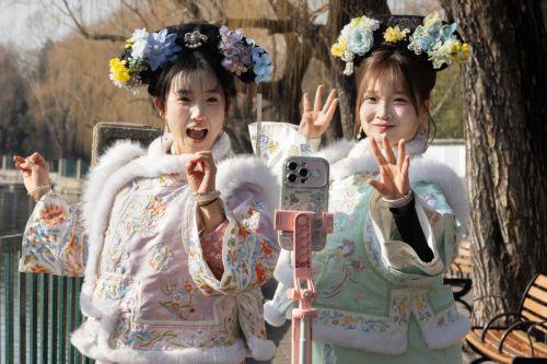 epa12681827 People dressed in traditional clothing film a social media video at a park in Beijing, China, 26 January 2026. In Beijing, tourists can purchase services such as traditional clothing rental, make-up application, hair up-dos, and photography to enhance their cultural experience of the city.  EPA/JESSICA LEE
