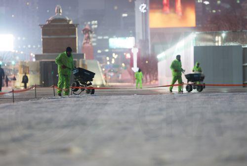 epa12699133 Workers spray a deicing agent onto Gwanghwamun Plaza in Seoul, 02 February 2026, following heavy snowfall overnight.  EPA/YONHAP SOUTH KOREA OUT