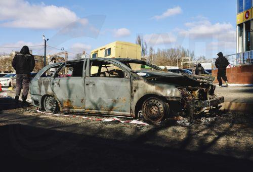epa12719862 Ukrainian people stand near a burned car at the site of a Russian strike in Odesa, southwestern Ukraine, 09 February 2026, amid the Russian invasion. At least one person was killed and two others injured after a drone hit a residential area, damaging a high-rise building and a gas pipeline, according to the State Emergency Service of Ukraine. ...