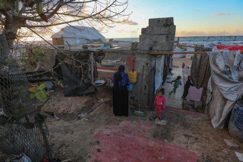 epa12774677 A displaced Palestinian woman prepares iftar in the remains of a destroyed building among makeshift tents before breaking their fast during the holy month of Ramadan, near the beach in Gaza City, 24 February 2026. Muslims around the world celebrate the holy month of Ramadan by praying during the nighttime and abstaining from eating, drinking,...