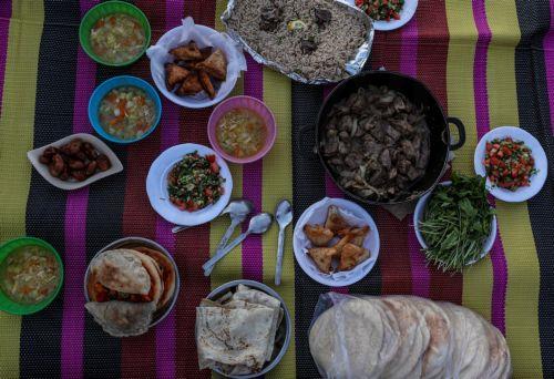 epa12774709 A prepared iftar meal of a displaced Palestinian family lies on a carpet at sunset in the remains of a destroyed building among makeshift tents during the holy month of Ramadan, near the beach in Gaza City, 24 February 2026. Muslims around the world celebrate the holy month of Ramadan by praying during the nighttime and abstaining from eating,...