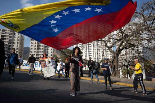 epa12793160 A person waves a Venezuelan flag during a march in Caracas, Venezuela, 03 March 2026. Hundreds of Chavistas march to demand the release of Nicolas Maduro and his wife Cilia Flores two months after their capture by US military forces following an attack on Caracas and three nearby regions.  EPA/Ronald Peña R