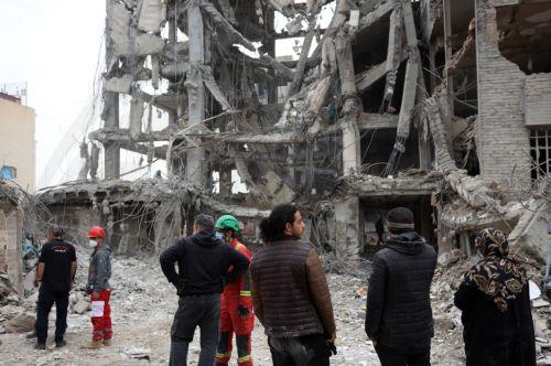 epa12813997 Iranians gather in front of their damaged residential buildings in central Tehran, Iran, 12 March 2026. A joint Israeli and US military operation continues to target multiple locations across Iran since the early hours of 28 February 2026.  EPA/ABEDIN TAHERKENAREH